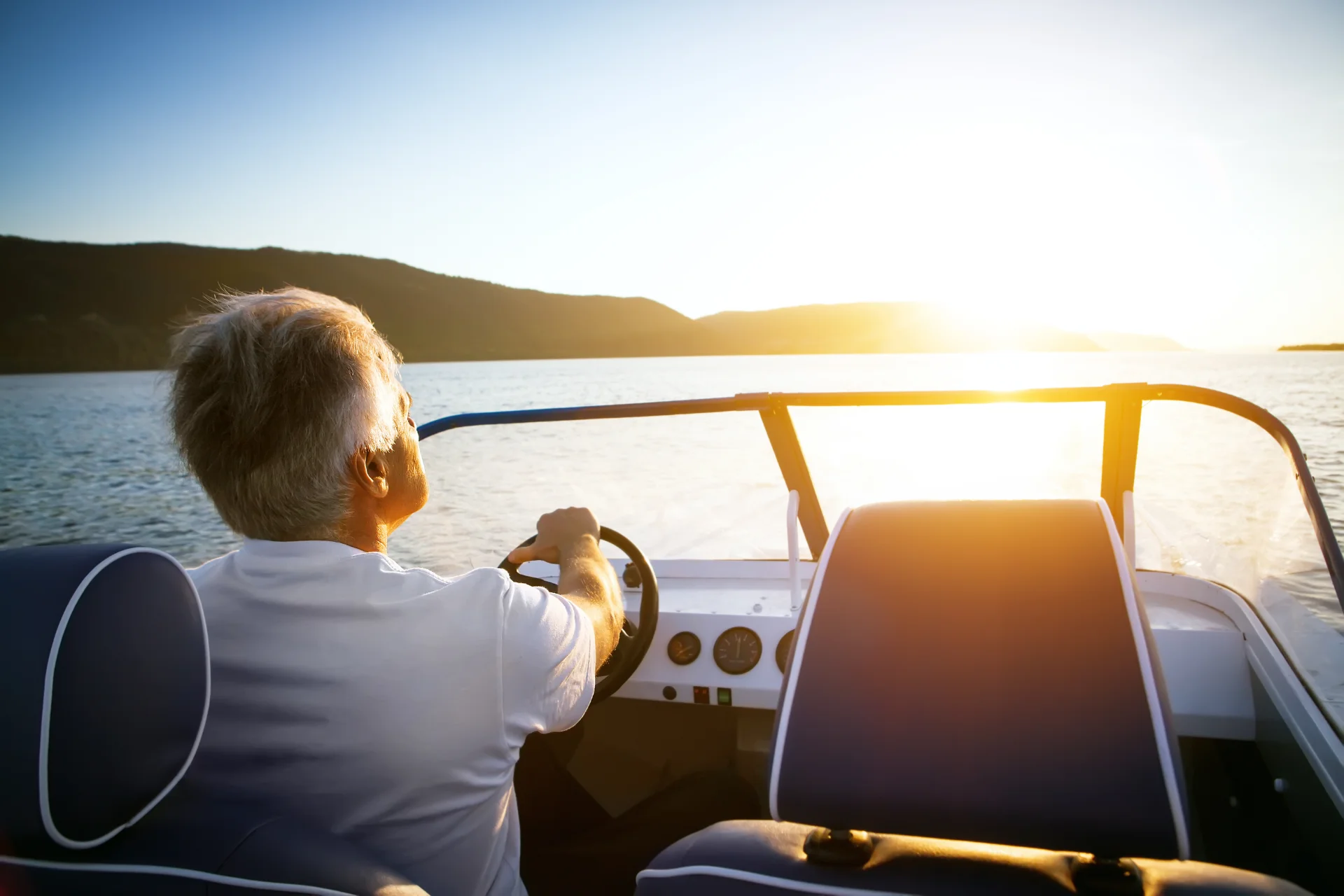 Man driving boat into sunset peacefully